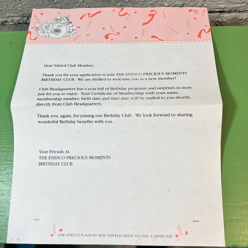 May include: A folded letter from The Enesco Precious Moments Birthday Club. The top of the letter has a pink border with a cartoon design. The letter's text welcomes new members and describes birthday programs.