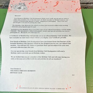 May include: A pink and white Birthday Club letter with decorative elements. The letter includes text about membership, a welcome message, and information about figurines and newsletters. The letter is from The Enesco Precious Moments Birthday Club.