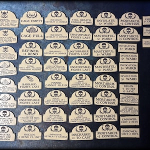 May include: A collection of beige game tokens with black text and skull graphics. The tokens have various phrases like "Unstoppable Fights Last" and "Mortarch +3 Control". The tokens are arranged on a dark blue surface.