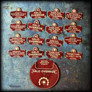 May include: A collection of burgundy-colored game tokens with white text. The tokens have various phrases like "Halo Override" and "Overload Units Gain +2" Move." The tokens are for a tabletop game.