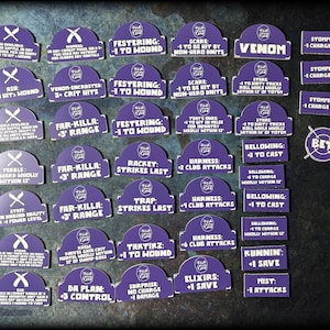 May include: A set of 24 purple and white tokens with various text and symbols. The tokens are shaped like arches and have a white border. The text on the tokens includes phrases like "Festering: -1 to Wound", "Far-Killa: +3' Range", and "Venom-Encrusted: 5+ Crit Hits".