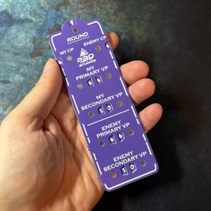 Puede incluir: Un rastreador de juego morado con texto blanco y remaches plateados. El rastreador tiene secciones para "Round", "My CP", "Enemy CP", "My Primary VP", "My Secondary VP", "Enemy Primary VP" y "Enemy Secondary VP". El texto "Pro Painted Studios" también es visible.