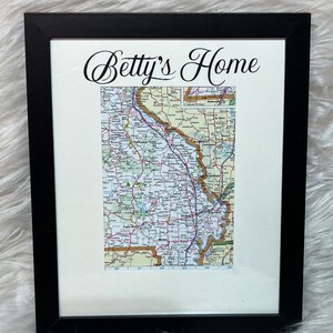 May include: A black framed picture with a white mat. The picture contains a map of a region with the text "Betty's Home" at the top.