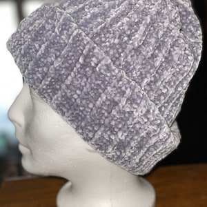 Puede incluir: Un gorro de punto gris y peludo. El gorro está en una cabeza de maniquí blanca.