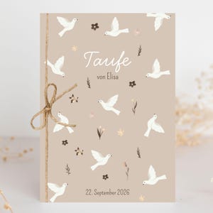 Peut inclure: Une carte rectangulaire beige ornée d'illustrations de colombes blanches, de petites fleurs marron foncé et de brindilles. Le texte indique Taufe von Elisa et 22. September 2026. Une ficelle de jute naturelle est nouée sur le côté gauche.