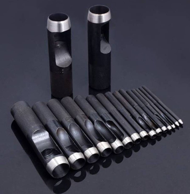 May include: A set of 17 black metal hole punch tools of varying sizes. The tools are arranged in a row, with the largest tool at the left and the smallest tool at the right. The tools are used for punching holes in leather, fabric, and other materials.