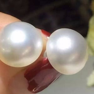 May include: A pair of white pearl earrings. The pearls are round and have a smooth, glossy finish.