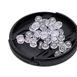 May include: A black plastic container filled with clear plastic rings. The rings are small and round, and they are arranged in a random pattern.