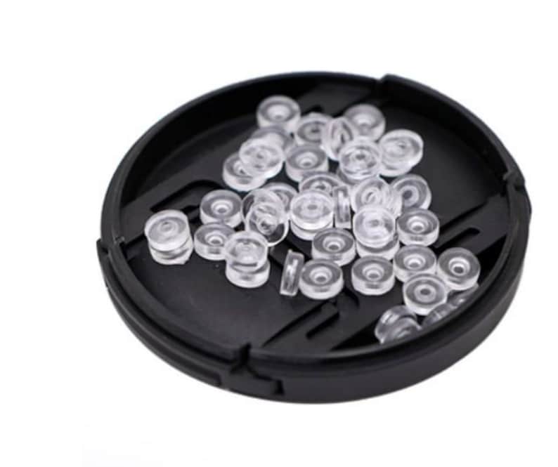 May include: A black plastic container filled with clear plastic rings. The rings are small and round, and they are arranged in a random pattern.