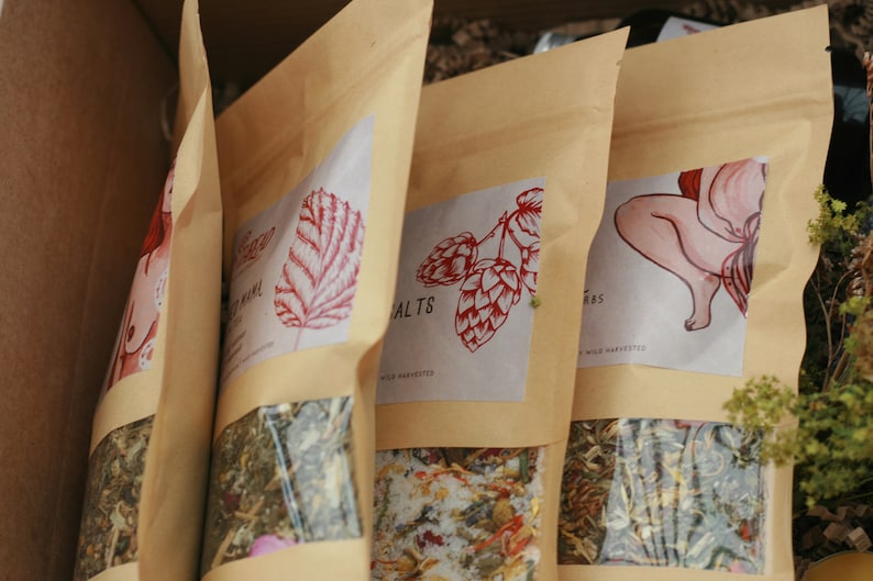 May include: Four brown paper bags with different illustrations and text. The bags contain loose leaf herbs and are labeled "Herbal Salts", "Herbs", "Yoni Steam", and "Moon Mama".