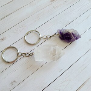 May include: Two crystal keychains, one clear quartz and one amethyst, with silver key rings and chains.