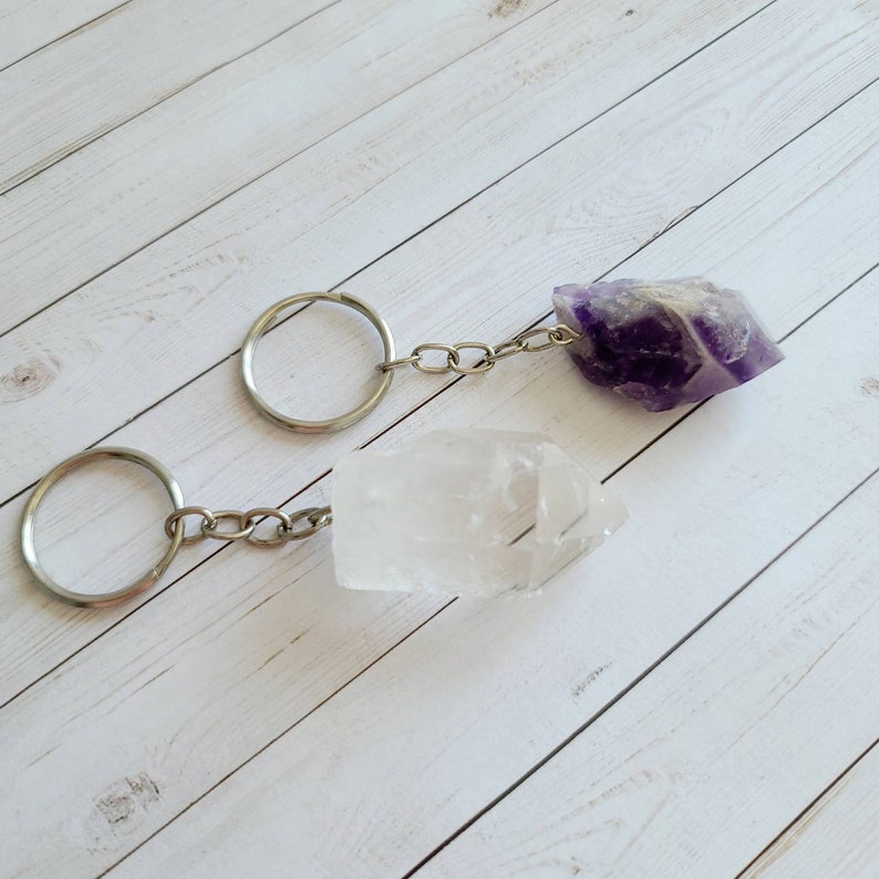 May include: Two crystal keychains, one clear quartz and one amethyst, with silver key rings and chains.