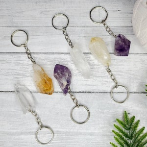 May include: Four crystal keychains with silver key rings. The crystals are clear, yellow, purple, and white.