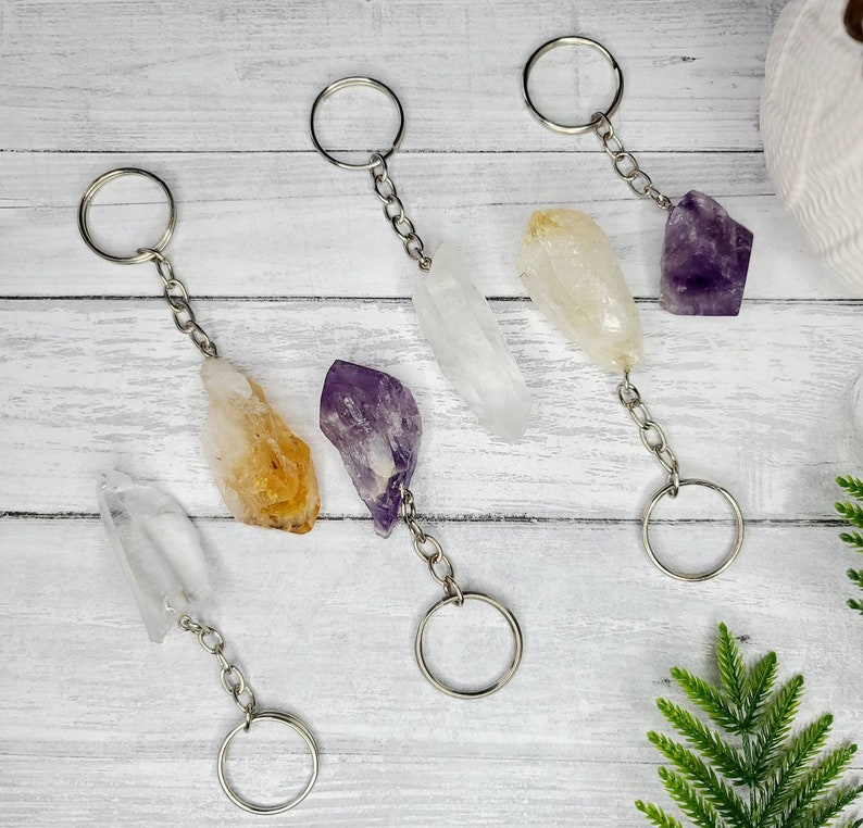 May include: Four crystal keychains with silver key rings. The crystals are clear, yellow, purple, and white.