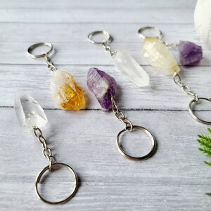 May include: Five crystal keychains with silver key rings and chains. The crystals are clear, yellow, purple, and white.