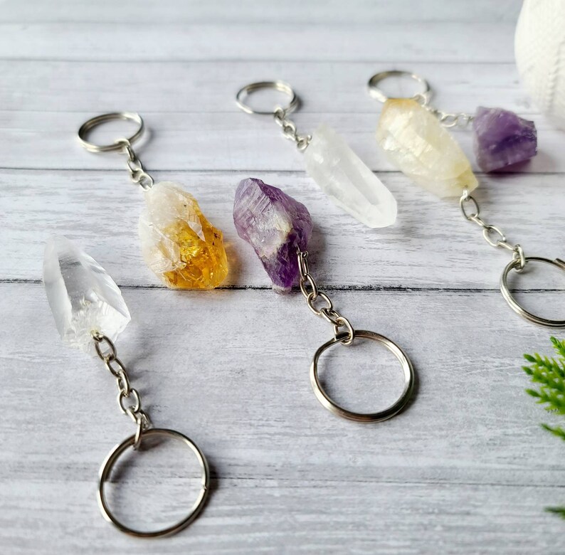 May include: Five crystal keychains with silver key rings and chains. The crystals are clear, yellow, purple, and white.