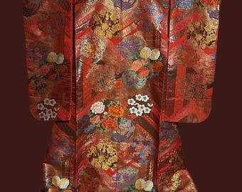 May include: A traditional Japanese red and gold kimono with intricate floral patterns and a red trim. The kimono is made of silk and has a luxurious feel.