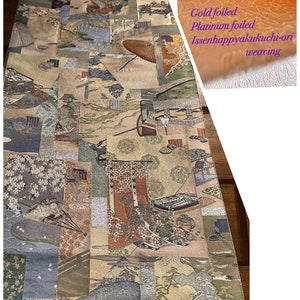 May include: A traditional Japanese table runner with a gold and platinum foiled design. The runner features a patchwork of scenes with birds, flowers, and geometric patterns. The text "本金當 壱千八百门 プラチナ" is woven into the fabric.
