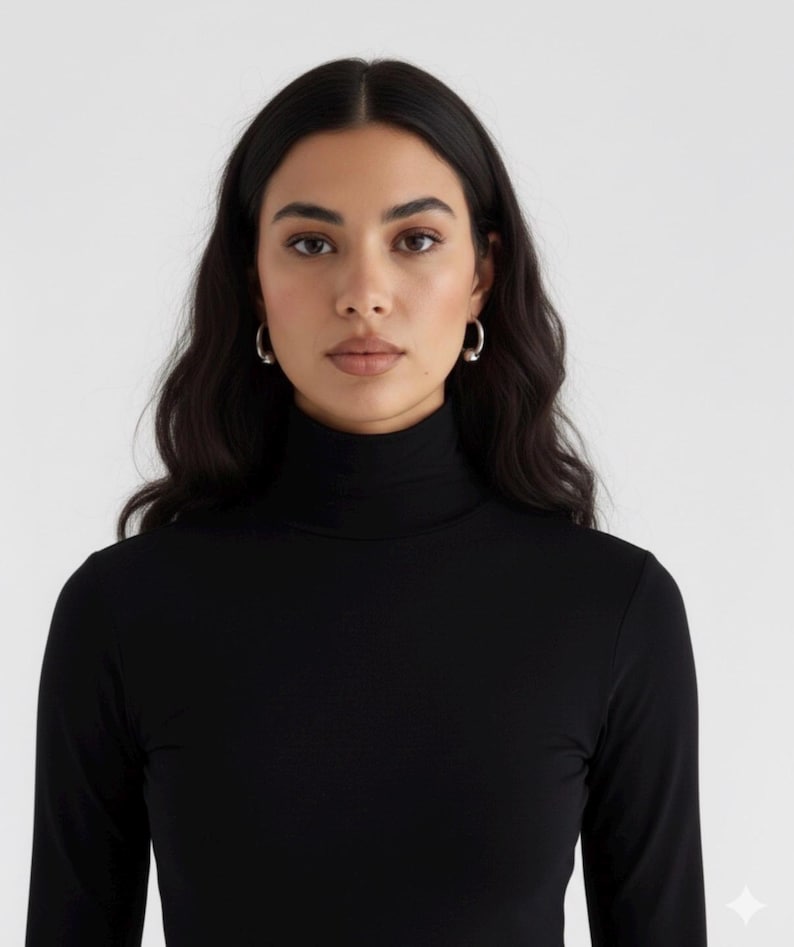 May include: A black long-sleeve shirt featuring a high turtleneck collar. The garment is made of a solid black fabric with a smooth texture, providing full coverage up to the neck. The design is simple, focusing on the fitted silhouette and collar.