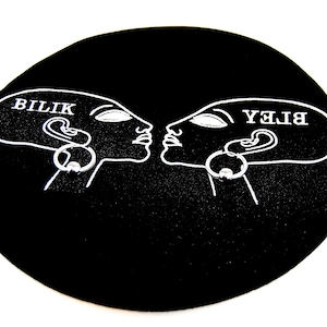 May include: A black circular display card featuring a white line art illustration of two profile heads facing each other. Each head has a silver-toned captive bead ring earring attached. The text BILIK is printed on the left head, and the text BLEY is printed on the right head in a mirrored orientation.