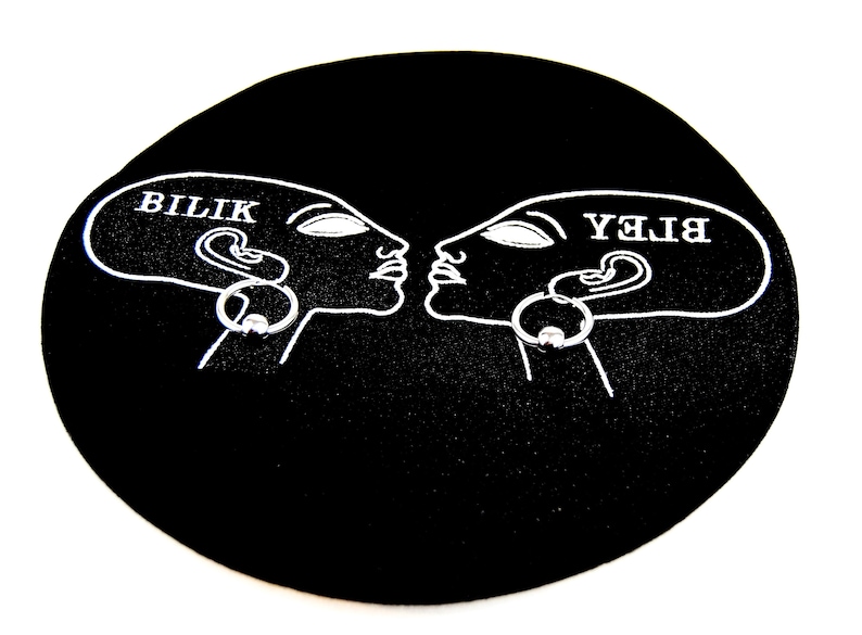 May include: A black circular display card featuring a white line art illustration of two profile heads facing each other. Each head has a silver-toned captive bead ring earring attached. The text BILIK is printed on the left head, and the text BLEY is printed on the right head in a mirrored orientation.