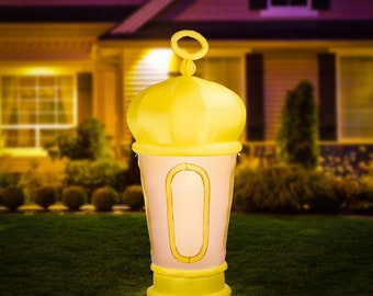 May include: An illuminated inflatable lantern, with a yellow top and base, and a light pink body. The lantern has gold trim and is on a green lawn. The background shows a house.