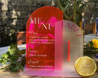 May include: Pink and white acrylic table number card with the number "1" and a menu with the text "MENU" and the words "Magret de canard", "Sauce acidulé à la myrtille", "Gâteau de champignons", "Fromage", "Plateau du berger", "Dessert", "Gâteau pêche lavande".
