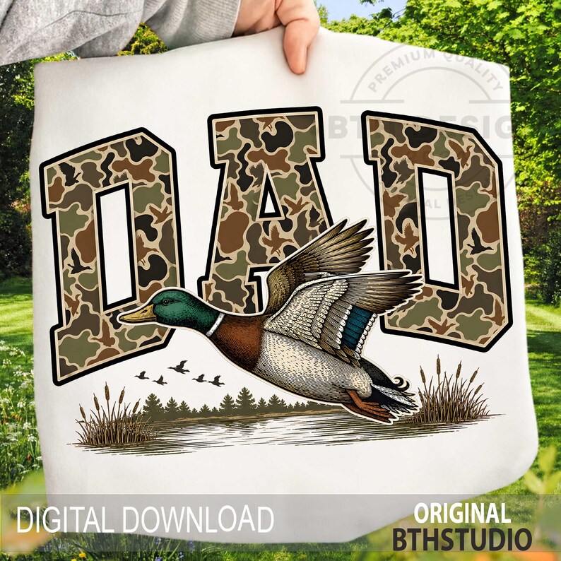 May include: White graphic with the word "DAD" in a camouflage pattern and black outline. A detailed illustration of a flying mallard duck is below the text, with a lake and reeds. The words "DIGITAL DOWNLOAD" and "ORIGINAL BTHSTUDIO" are also visible.