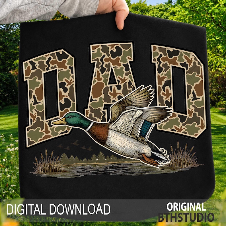 May include: Black tote bag with the word "DAD" in camouflage lettering. A detailed illustration of a flying mallard duck is featured below the text. The words "DIGITAL DOWNLOAD" and "ORIGINAL BTHSTUDIO" are at the bottom.