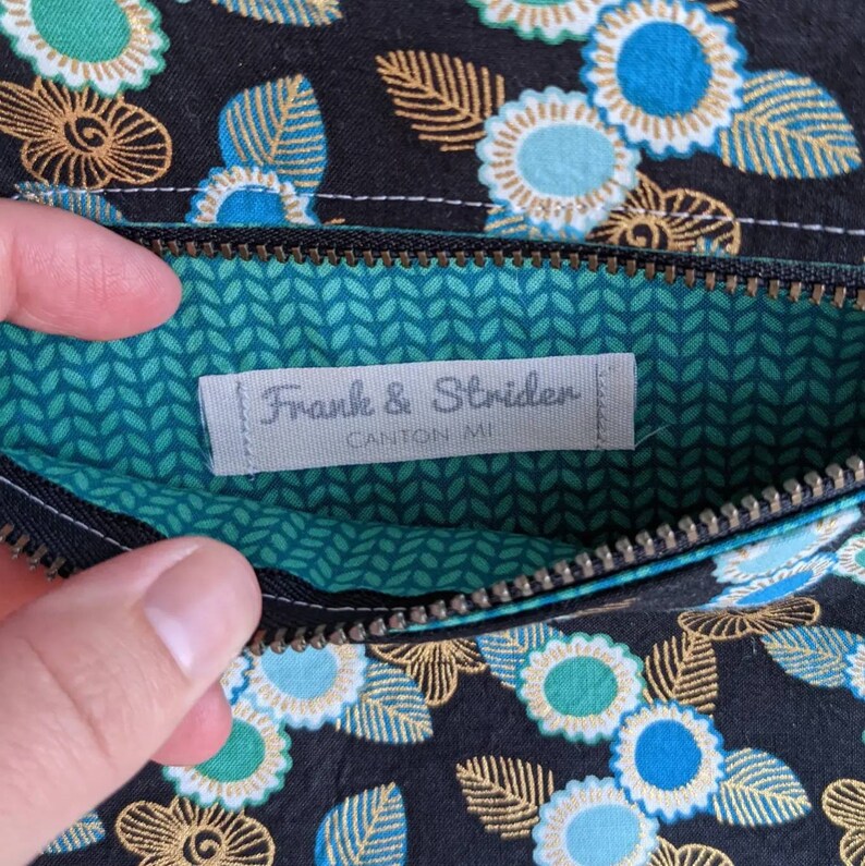 May include: A black zippered pouch with a green and white patterned lining. The pouch has a label that reads "Franke & Striden, Canton MI".