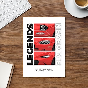 May include: A white sticker with illustrations of three red car front ends. The sticker has the words "LEGENDS" and "NEVER DIE" in black and white. The text "MAZDABAY" is also included on the sticker.