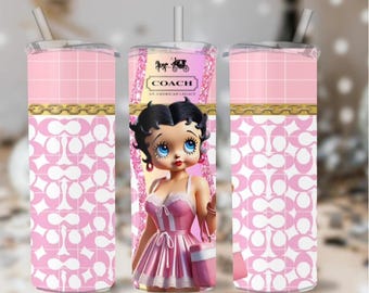 May include: Pink and white tumbler with a repeating pattern and a gold band. The central design features Betty Boop with the Coach logo and the text "An American Legacy". The tumbler includes a straw.