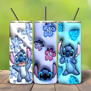 May include: Three stainless steel tumblers with straws, each featuring a different design of the character Stitch. The tumblers have a white, lavender, and light blue background with floral and snowflake patterns. The character is blue with pink ears.