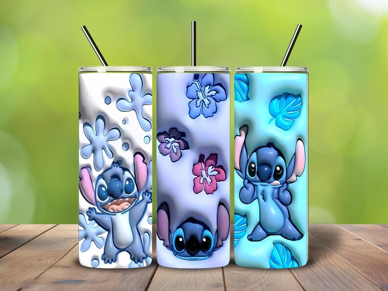 May include: Three stainless steel tumblers with straws, each featuring a different design of the character Stitch. The tumblers have a white, lavender, and light blue background with floral and snowflake patterns. The character is blue with pink ears.