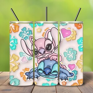 May include: A set of three stainless steel tumblers with black straws. Each tumbler features a cartoon illustration of Stitch and Angel, surrounded by colorful flowers and hearts. The background is a light cream color.