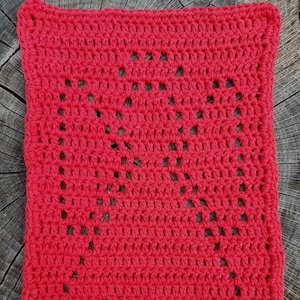 May include: A red crocheted dishcloth with a diamond pattern. The dishcloth is made with a single crochet stitch and has a textured surface.