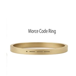 Pode incluir: Um anel dourado com uma banda plana e retangular. O anel apresenta um design de código Morse gravado na superfície. O texto "Morce Code Ring" está acima do anel.