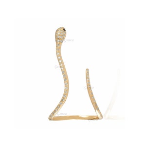 May include: A gold snake ring set with clear cubic zirconia stones. The snake is curled around the finger and has a pointed tail.
