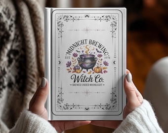 May include: A white book cover with the text "MIDNIGHT BREWING" and "Witch Co." in a decorative font. The cover features a cauldron with steam, pumpkins, and floral accents. The book is held by a person wearing a white sweater.