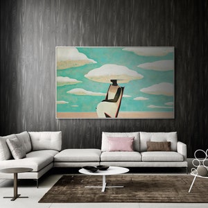 May include: A white sofa with a pink throw pillow and a brown throw pillow. A white coffee table sits in front of the sofa. A framed painting of a person sitting on a chair with clouds above their head hangs on the wall behind the sofa.
