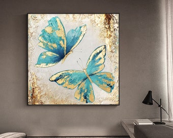 May include: A painting of two blue butterflies with gold accents on a white background. The butterflies are in flight and have their wings spread out.