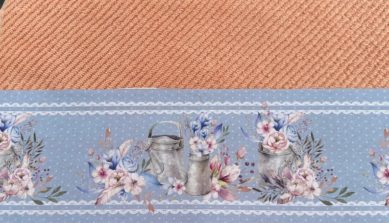 Puede incluir: Un pa&ntilde;o de cocina azul y blanco con un borde de encaje blanco. El patr&oacute;n presenta tres regaderas vintage con ramos de flores.