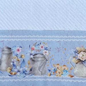 Puede incluir: Una tela azul y blanca con un patr&oacute;n, un borde de encaje blanco y una fila de regaderas plateadas con arreglos florales.