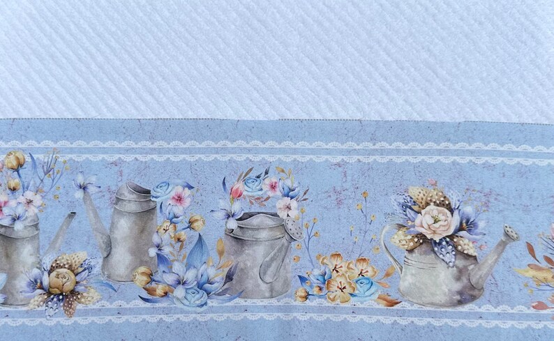 Puede incluir: Una tela azul y blanca con un patr&oacute;n, un borde de encaje blanco y una fila de regaderas plateadas con arreglos florales.