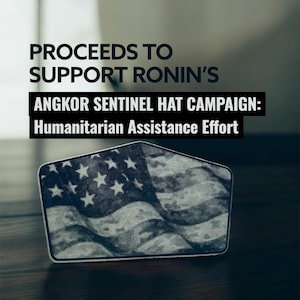 May include: A rectangular patch featuring a stylized American flag design in shades of gray and white. The text reads "PROCEEDS TO SUPPORT RONIN'S ANGKOR SENTINEL HAT CAMPAIGN: Humanitarian Assistance Effort."