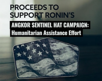 May include: A rectangular patch featuring a stylized American flag design in shades of gray and white. The text reads "PROCEEDS TO SUPPORT RONIN'S ANGKOR SENTINEL HAT CAMPAIGN: Humanitarian Assistance Effort."