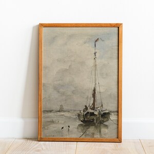 May include: A framed watercolor painting of a sailboat on a beach with a cloudy sky. The sailboat has a brown hull and a white sail. There are three small birds in the foreground.