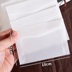 K&ouml;nnte beinhalten: Ein Stapel durchscheinender wei&szlig;er Umschl&auml;ge, die 17,8 cm x 25,4 cm gro&szlig; sind. Die Umschl&auml;ge bestehen aus einem d&uuml;nnen, zarten Material und eignen sich perfekt zum Versenden von Briefen oder Karten.
