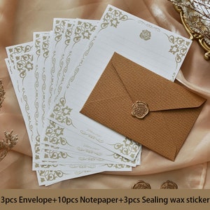 K&ouml;nnte beinhalten: Ein Set aus 10 wei&szlig;en Briefb&ouml;gen mit goldenen Dekorranden und 3 braunen Umschl&auml;gen mit einem goldenen Wachssiegel. Die Briefb&ouml;gen tragen den Text "Writing paper".  3pcs Envelope+10pcs Notepaper+3pcs Sealing wax sticker