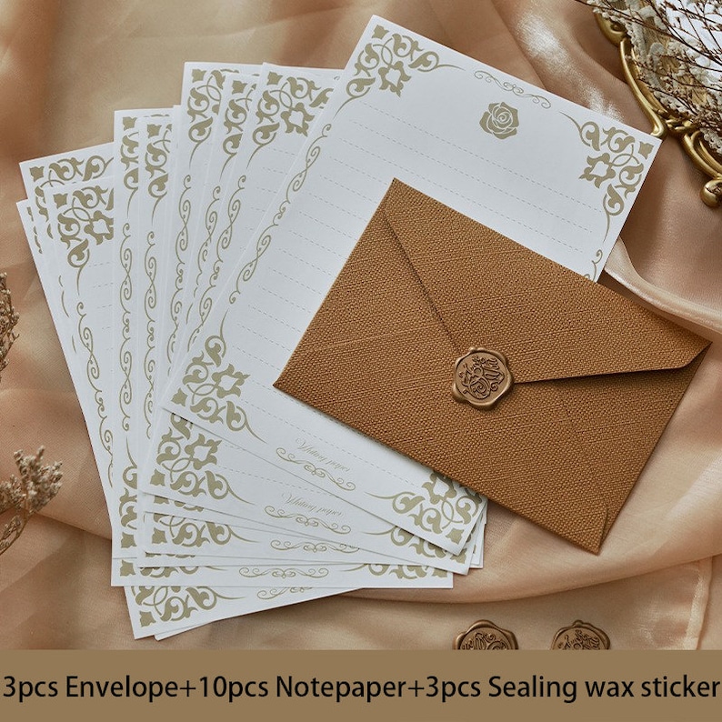 K&ouml;nnte beinhalten: Ein Set aus 10 wei&szlig;en Briefb&ouml;gen mit goldenen Dekorranden und 3 braunen Umschl&auml;gen mit einem goldenen Wachssiegel. Die Briefb&ouml;gen tragen den Text "Writing paper".  3pcs Envelope+10pcs Notepaper+3pcs Sealing wax sticker